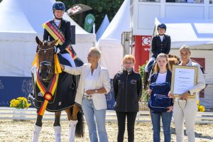 Christiane Ulmker ritt die selbstgezogene Be my Sunshine in Bilderbuchmanier zum Titel der Bundeschampionesse bei den dreijährigen Stuten und Wallachen und erhielt zudem den BMLEH-Tierschutzpreis aus der Hand von Susanne Ridderbusch (rechts im Bild). Foto: Gesina Grömping/Equitaris